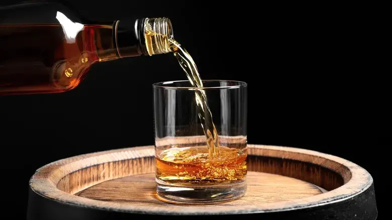 whisky versé depuis une bouteille dans un verre illustrant l’oxydation et l’aération après ouverture