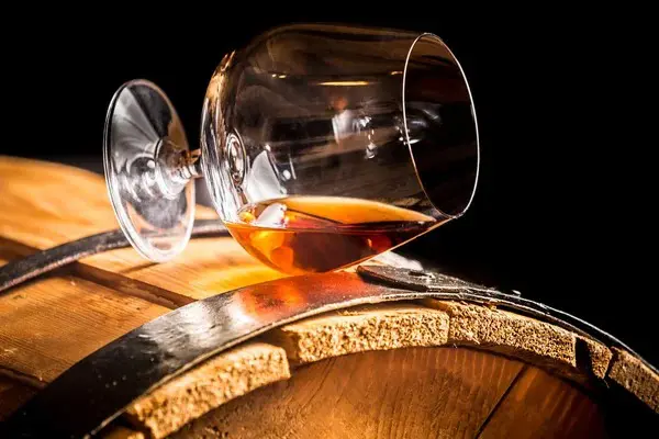 verre de whisky posé sur un fût en chêne illustrant le vieillissement du whisky