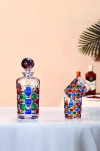 carafe à whisky colorée avec deux verres assortis sur table, un verre incliné