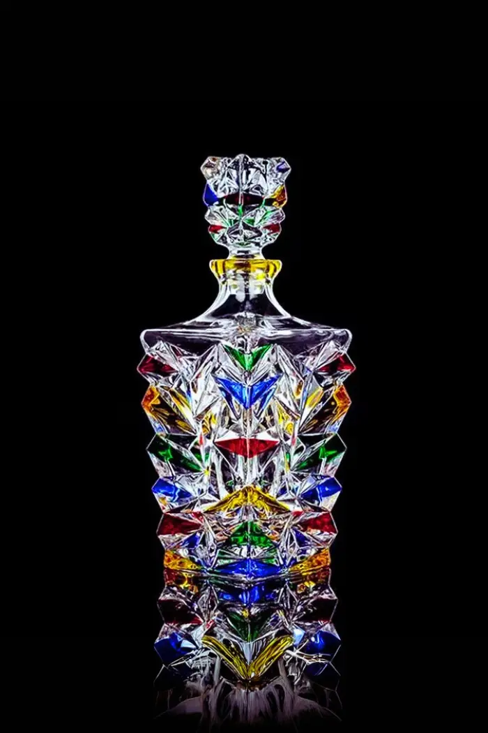 carafe italienne colorée pour whisky - bouteille en verre taillé multicolore sur fond noir.