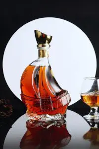 carafe à whisky bateau en verre sur fond noir avec disque blanc et verre ballon
