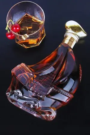 carafe à whisky bateau en verre couchée près d’un verre à whisky et cerises