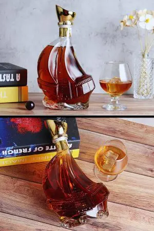 carafe à whisky bateau en verre sur table, bouchon doré et verre ballon ambré