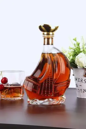 carafe à whisky bateau en verre sur surface sombre avec verre à whisky et cerises