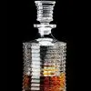 carafe à whisky en verre cannelé sur fond noir, partiellement remplie