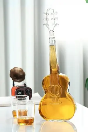 carafe à whisky guitare en verre remplie posée sur table avec deux verres
