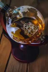 détail carafe globe sur base bois montrant le navire en verre interne