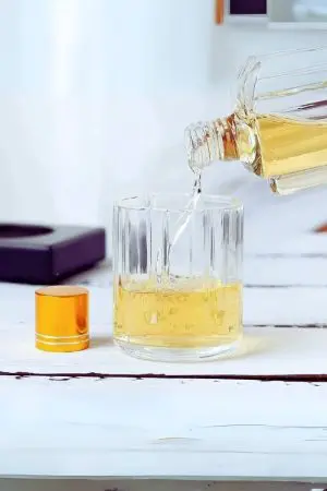 carafe à whisky revolver bouchon doré - versement de boisson claire dans un verre.
