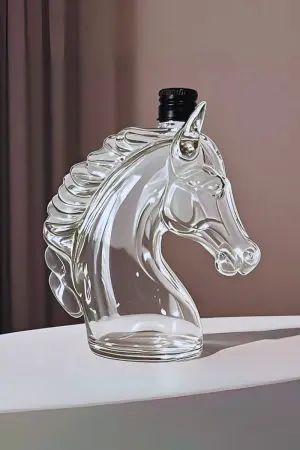 carafe à whisky tête de cheval en verre vide posée sur table blanche avec bouchon noir