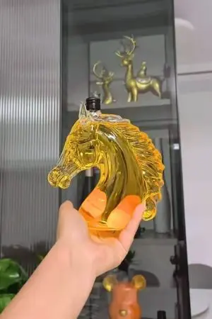 carafe à whisky tête de cheval tenue en main remplie de liquide ambré