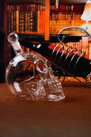 carafe à whisky tête de mort en verre vide avec bouchon facetté, fond bibliothèque