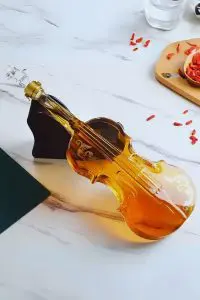 carafe à whisky violon couchée sur socle noir, liquide ambré, surface marbrée