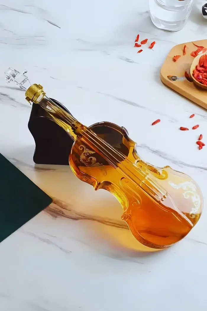 carafe à whisky violon couchée sur socle noir, liquide ambré, surface marbrée