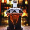 carafe à whisky diamant en verre sur socle noir, liquide ambré, table en bois