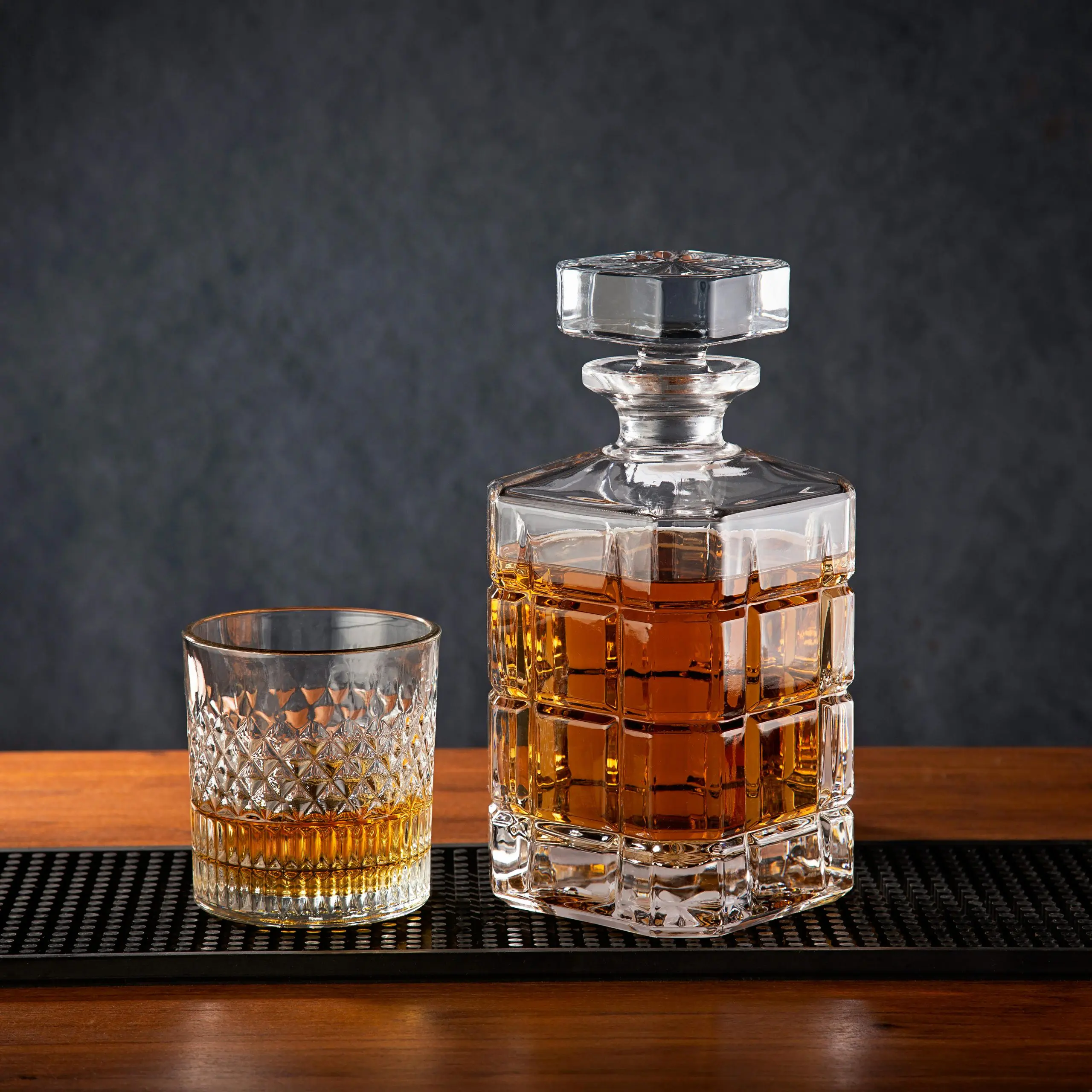 carafe à whisky en verre taillé accompagnée d’un verre tumbler, mise en valeur sur un comptoir en bois